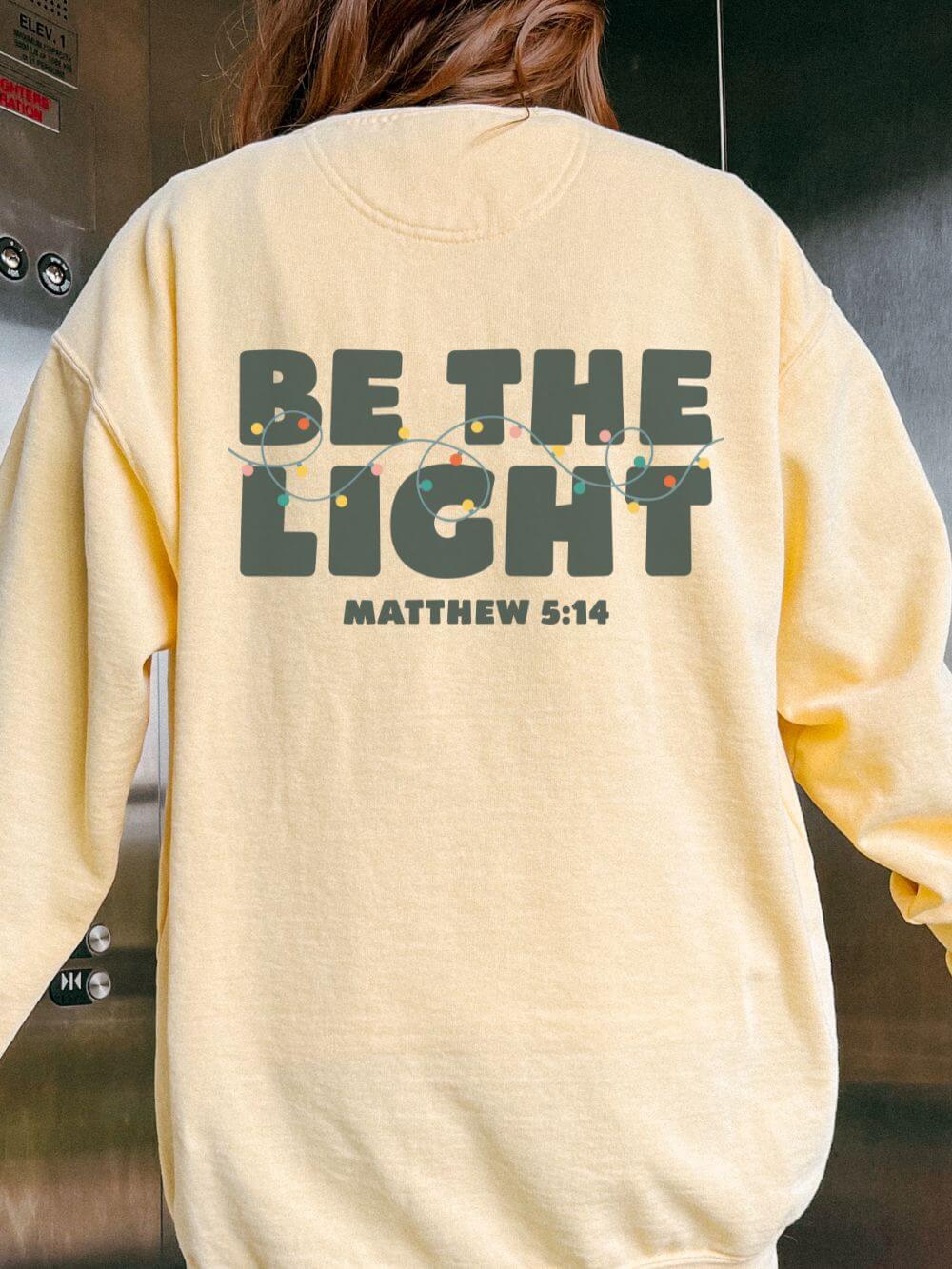 Be_the_Light_Back_Butter Be The Light Matthew 5:14 Christian Faith Comfort Colors Christmas Crewneck Sweatshirt - Image 1